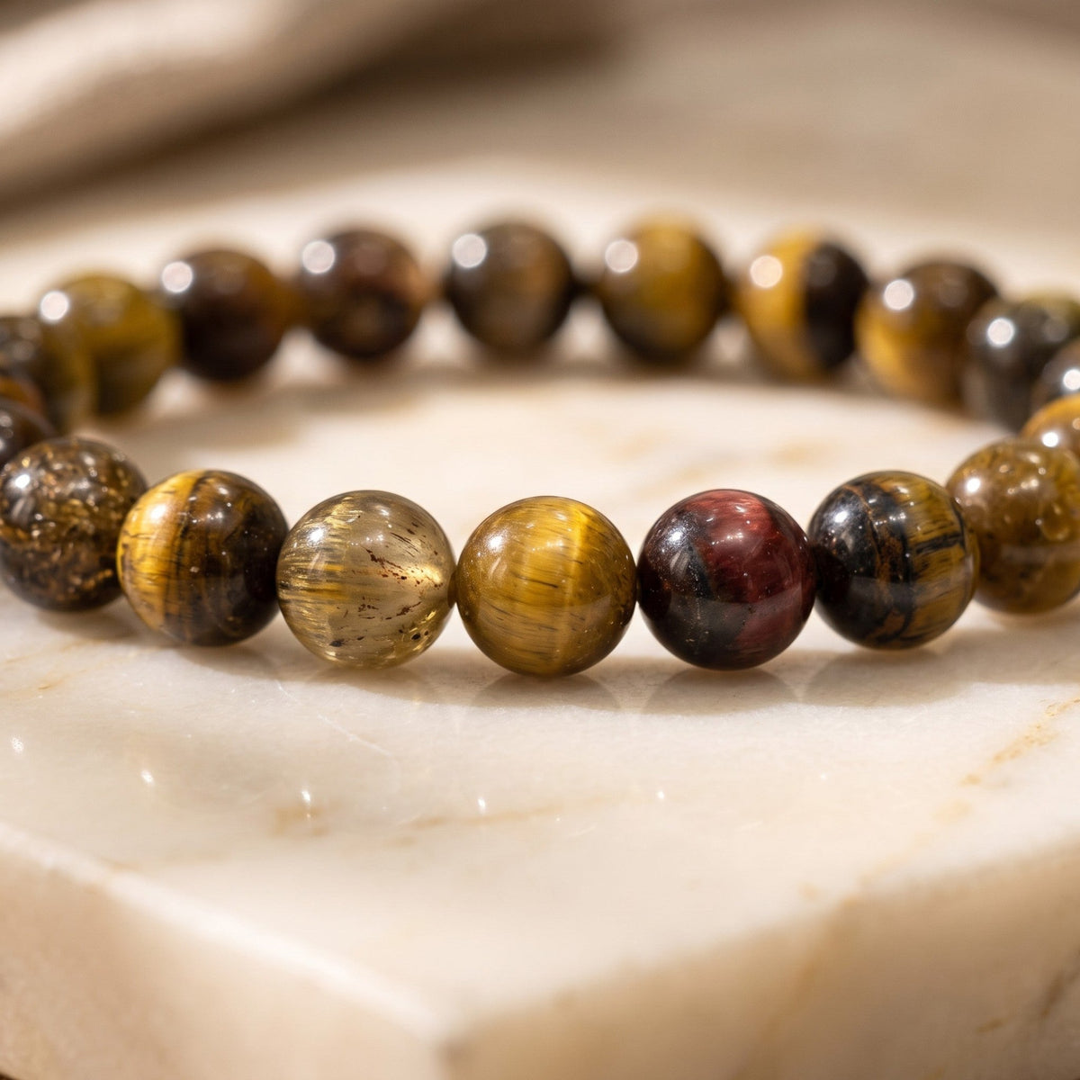 Shri Divya Ratan natural Tiger Eye crystal bead bracelet with golden-brown chatoyant shimmer on a marble surface