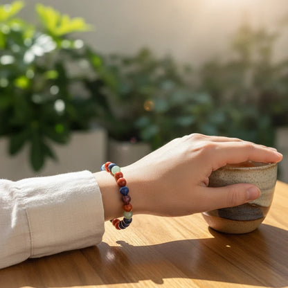 Shri Divya Ratan 7 chakra bracelet with natural gemstone beads worn on a wrist while holding a ceramic cup
