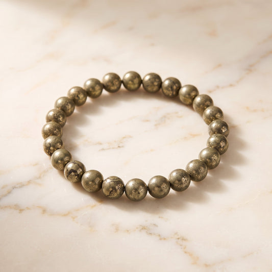 Shri Divya Ratan natural pyrite crystal bead bracelet with metallic gold shimmer on a marble surface.